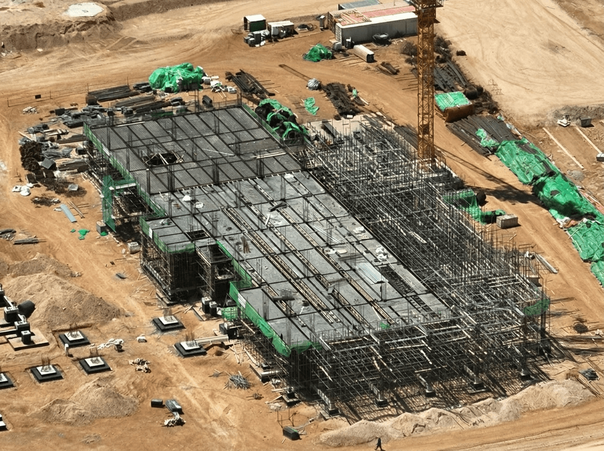 Aerial view of foundation construction with rebar and tower crane at the DRI plant site in Benghazi, Libya
